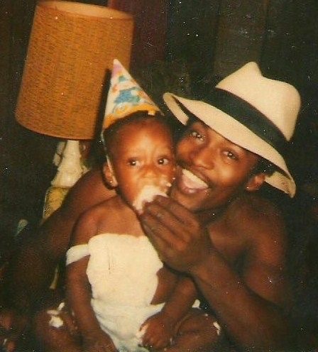 a father is feeding a piece of cake to his young daughter, who is wearing a birthday hat. both are smiling. the father is wearing a hat and the daughter is wearing a white dress. the image is a warm and loving portrayal of a fatherdaughter bond.