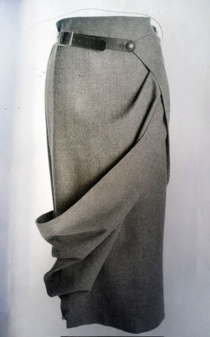 a gray wool skirt is featured with a draped, asymmetrical design and a black belt at the waist.