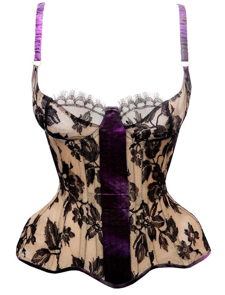 the image showcases a strapless corset made of beige lace with a black floral pattern overlay. the corset features a panel of purple velvet that runs vertically down the center. it has a detailed trim of delicate lace across the top edge. the straps are purple with gold metal hardware. the corset is designed with a fitted shape to accentuate the waist. the item is presented against a plain white background.