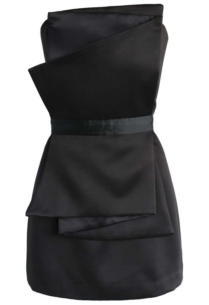 this is a black, strapless sheath dress in satin fabric with folded fabric detailing. the dress is fitted through the bodice and has a sash or belt at the waist. the fabric is folded in a layered manner in the middle.
