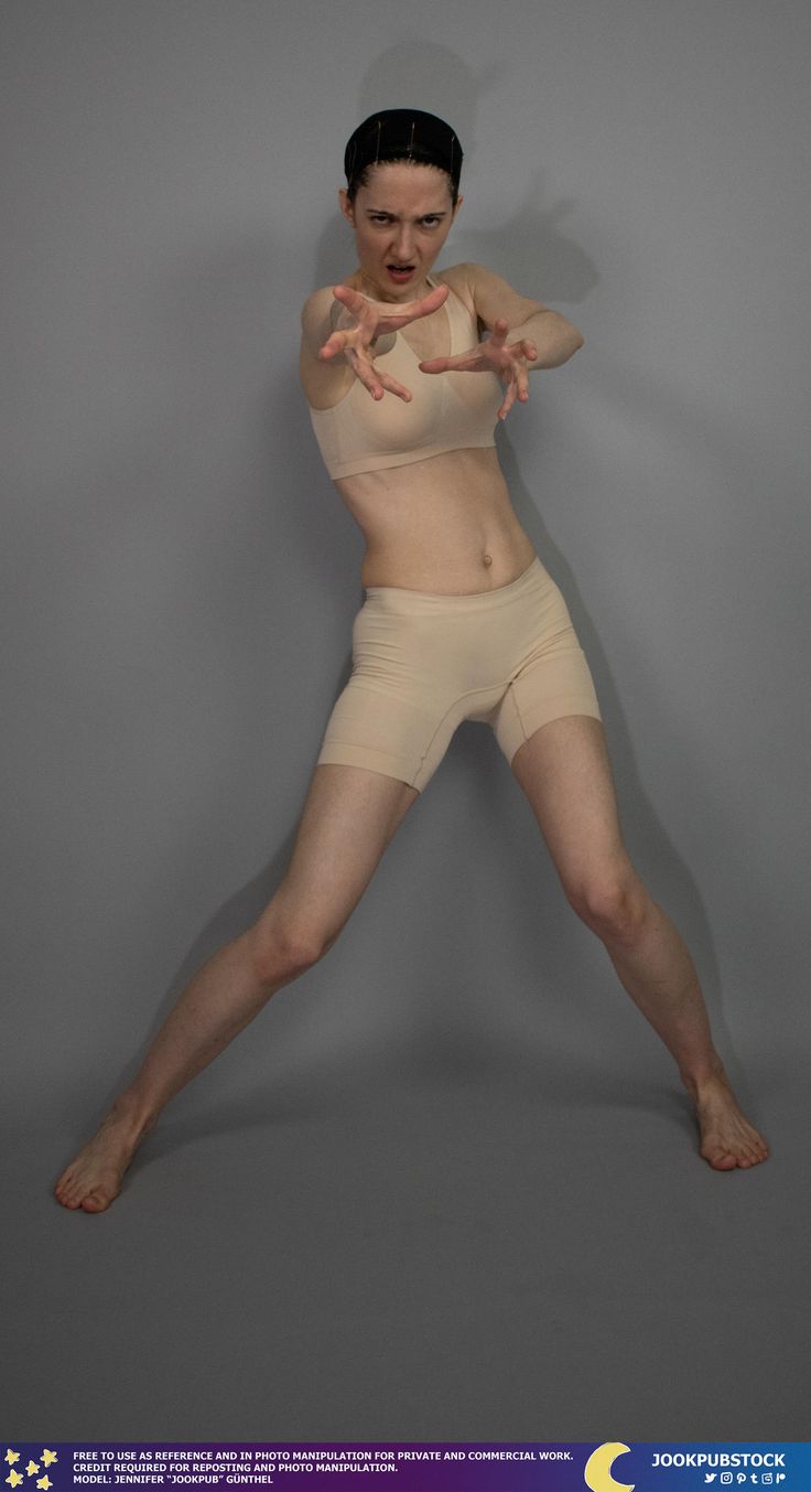 the image shows a fullbody shot of a young, slender woman with short dark hair. she is standing against a neutral gray background, in a dynamic pose with her arms outstretched, fingers spread, as if reaching or grabbing something. her facial expression is intense and serious. she is wearing a light beige sports bra and matching short shorts.  the overall mood is one of action and intensity. the image is clearly presented as a reference photo for artists and designers, suitable for photo manipulation for both personal and commercial use.
