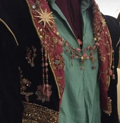 a closeup shot of a person wearing a traditional, festive garment. the fabric is richly embroidered with intricate designs and embellishments, including sequins, beads, and jewels. the garment is adorned with a long, ornate necklace with a starshaped pendant. the overall aesthetic is elegant and sophisticated, with a hint of vintage charm. the focus is on the intricate details of the embroidery and the luxurious materials used in its creation.