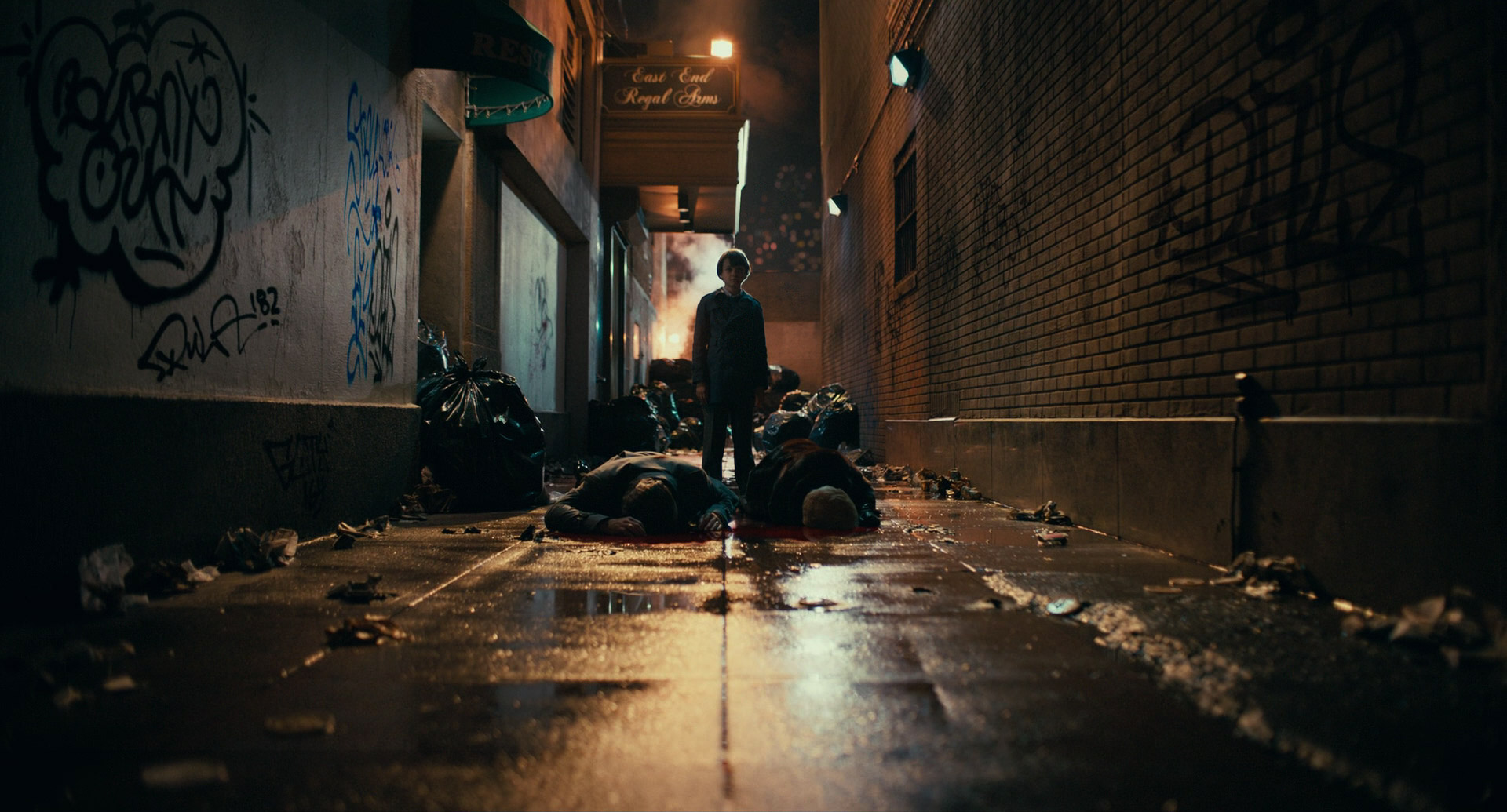 a man stands at the end of a dark and gritty urban alleyway, illuminated by a lone streetlight.  several bodies lay dead at his feet, reflecting in the wet pavement. trash bags and graffiti line the walls, emphasizing the scene's desolation and hinting at violence. the overall atmosphere is dark, suspenseful, and potentially depicting the aftermath of a crime or fight.