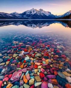 a stunning image of a serene lake nestled amongst majestic mountains. the reflection of the mountains in the crystalclear water creates a picturesque scene, while the colorful rocks that line the bottom of the lake add a touch of vibrancy. the overall feel of the image is one of peace, tranquility, and aweinspiring beauty.