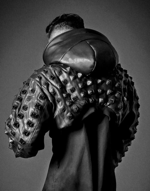a black and white portrait of a male model wearing a black leather jacket with a studded hood. the model is looking off camera and is slightly turned to the side. the lighting is dramatic and the image has a moody feel.