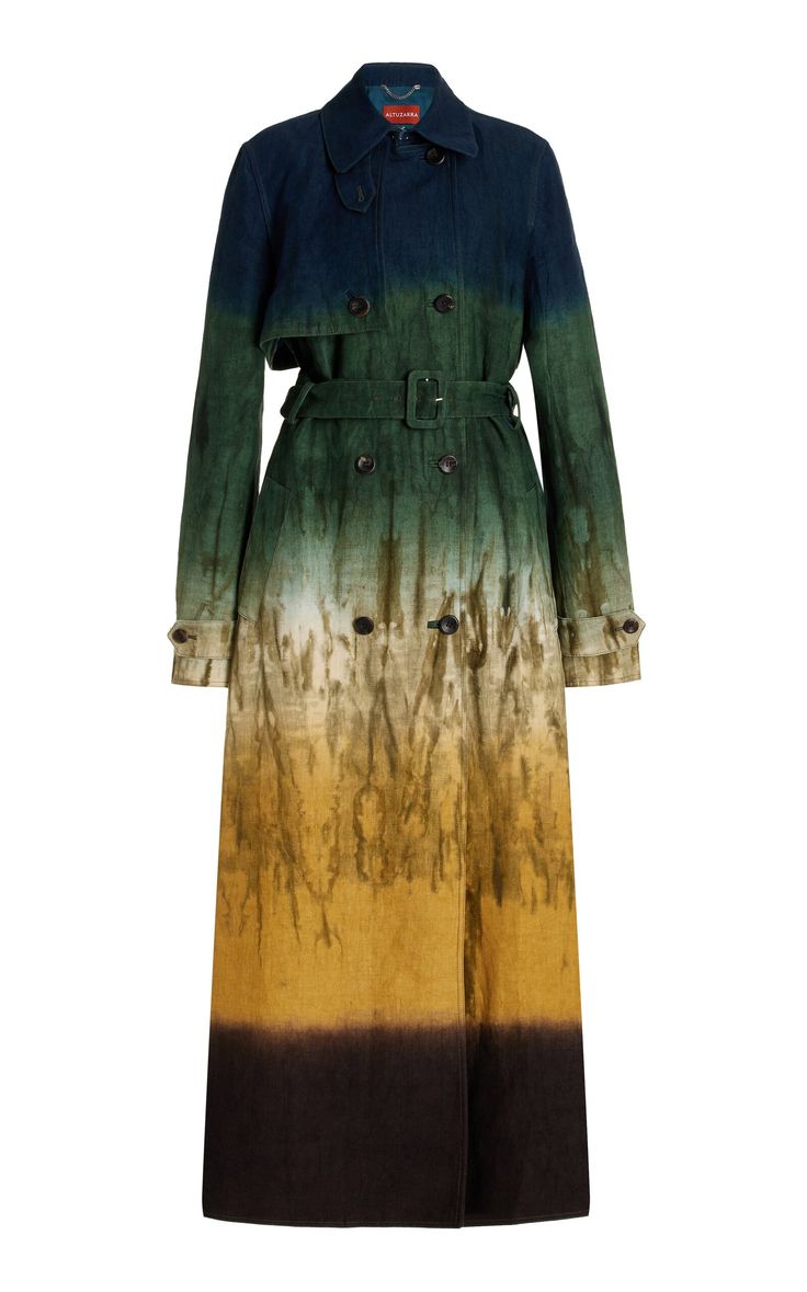 a long, doublebreasted ombre trench coat is displayed on a white background. the coat has a dark blue color at the top, which fades into green, then tan, and finally black at the bottom. a belt is tied around the waist.