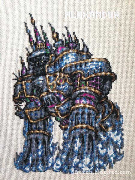 a closeup image of a crossstitched artwork depicting a fantasy creature with multiple heads, resembling a dragon or a monster, with intricate details and intricate patterns. the creature is primarily blue and grey with gold and purple accents, and it has a white background. the stitched fabric creates a detailed and textured appearance.