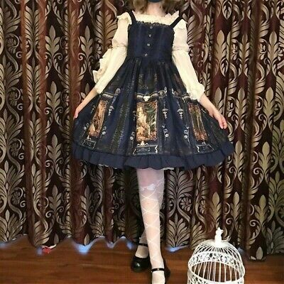 a person is wearing a navy blue and cream lolita fashion dress with a print of angels and stained glass windows. they are posing in front of a curtain. the image is taken from the chest up in a mirror selfie.
