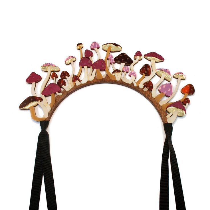 a whimsical mushroomthemed headband with black ribbon ties. the headband is adorned with an array of stylized wooden mushrooms in various sizes, colors, and patterns, including polka dots, attached to a wooden arc. the mushrooms give the headband a charming, fantastical appearance.