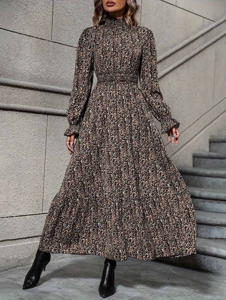 the image showcases a woman wearing a longsleeved maxi dress.  the dress features a high mock neck, a smocked waist, and a tiered skirt. the dress is adorned with a smallscale, allover floral print in shades of brown, black, and beige. the model is wearing black ankle boots and is posed on a staircase against a stone wall background. the overall style is elegant and autumnal.