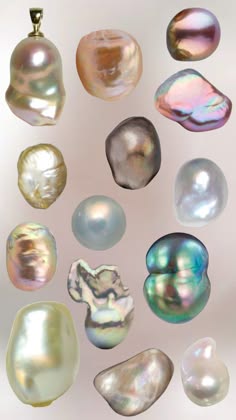 a collection of various pearls laid out on a white background. each pearl is different in size, color, and shape. the pearls are iridescent and have a smooth, glossy finish.  there is one pearl in the center of the image, that appears to be a pendant, because it has a gold loop at the top.  all the pearls are scattered randomly on the white background.