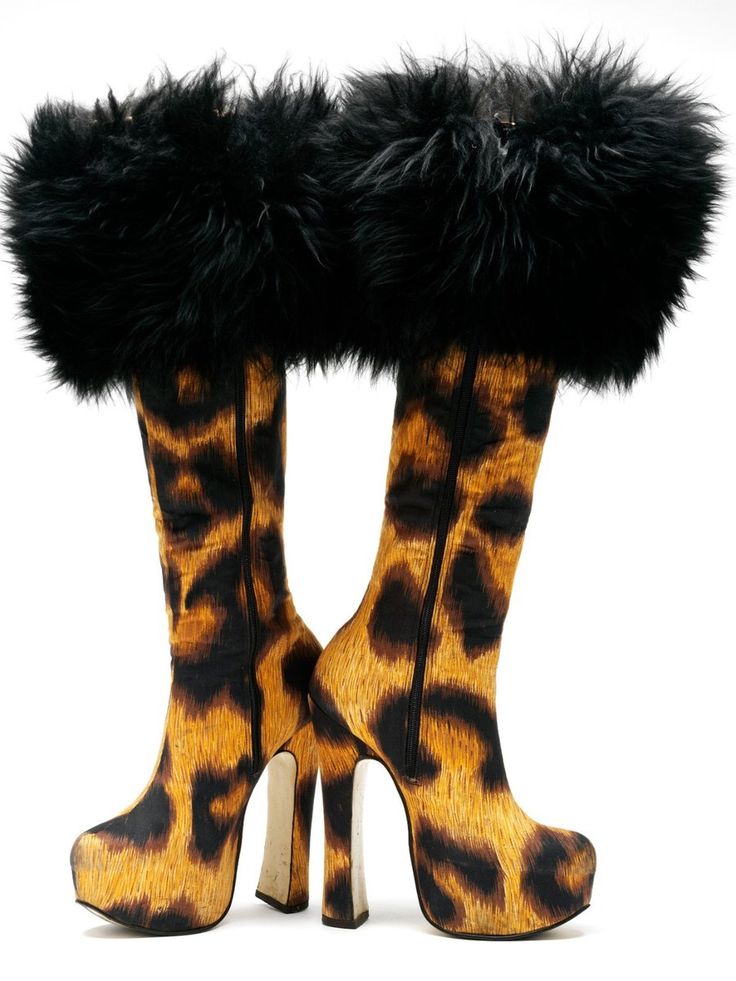 a pair of leopard print platform boots with black fur trim at the top of each boot. the boots have tall, block heels and are positioned sidebyside on a white background.