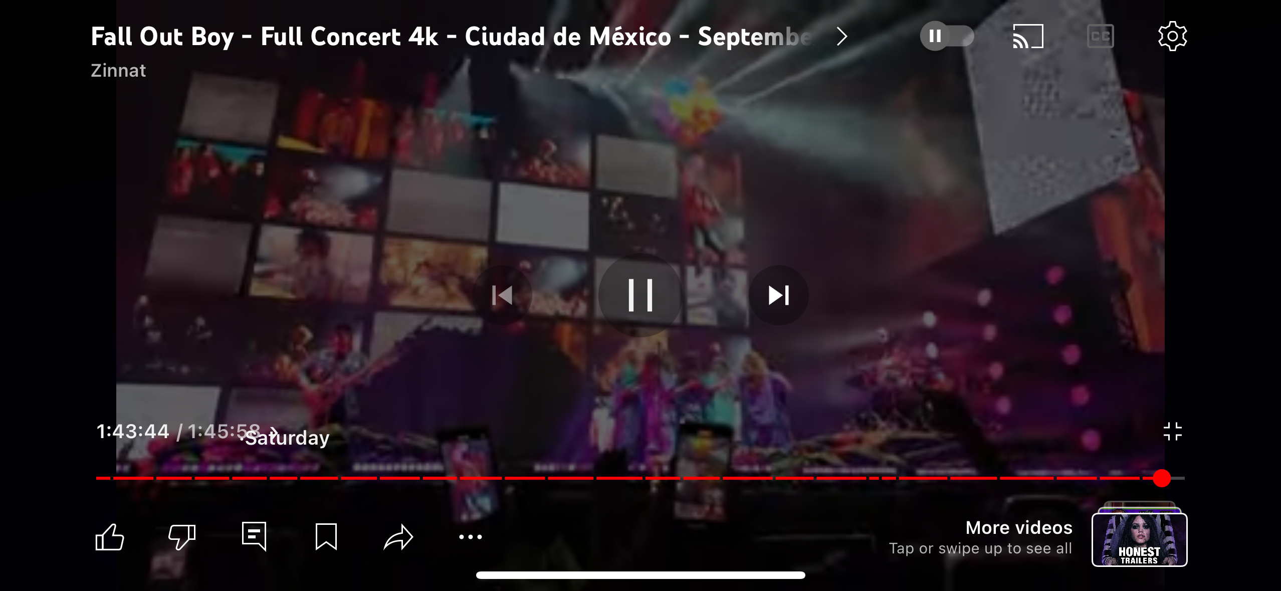 a screenshot of a video player on a mobile device, showing a live performance of fall out boy during a concert in mexico city. the video is titled "fall out boy  full concert 4k  ciudad de méxico  septembe" and is uploaded by the channel "zinnat". the screenshot captures the band performing on stage with the audience in the background. the video player has controls for playback, volume, and fullscreen mode. the bottom of the screen displays a row of icons for liking, disliking, commenting, bookmarking, sharing, and showing more options. there are also icons for fullscreen mode and a settings menu.  the image also displays a related video titled "honest trailers" in a small box.  the video is playing at a timestamp of 1:43:44/ 1:45:55. the image is a representation of the band's music and live performances.
