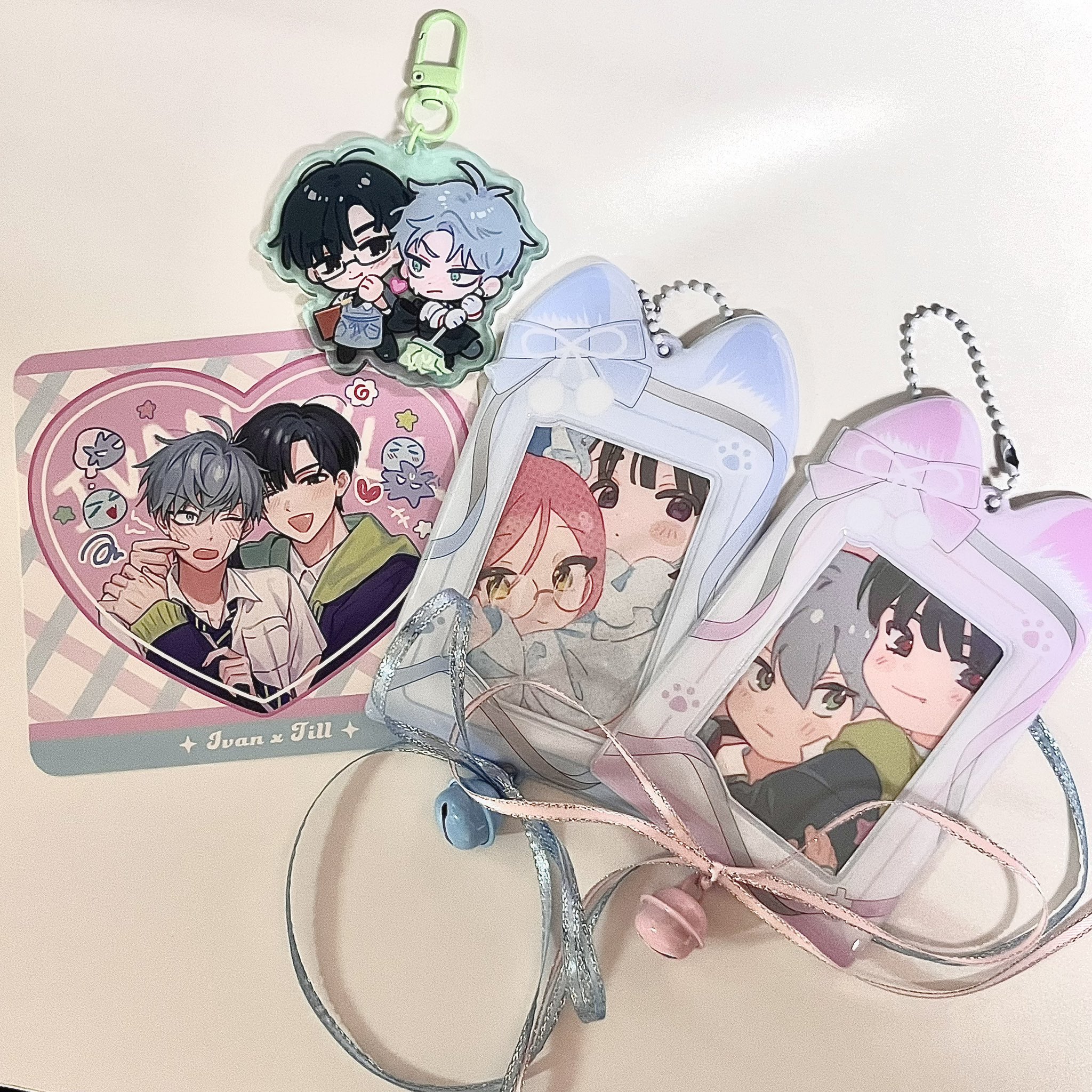 this image shows a collection of animethemed merchandise. there are three character card holders with lanyards. each holder features a different anime couple. the card holders are decorated with pastel pink and blue and have cute cat ear details. there is a heartshaped sticker with an anime couple on it, as well as a keychain with a cute anime boy and girl on it. overall, the image is very cute and features a collection of anime merchandise that would be a perfect gift for any fan.