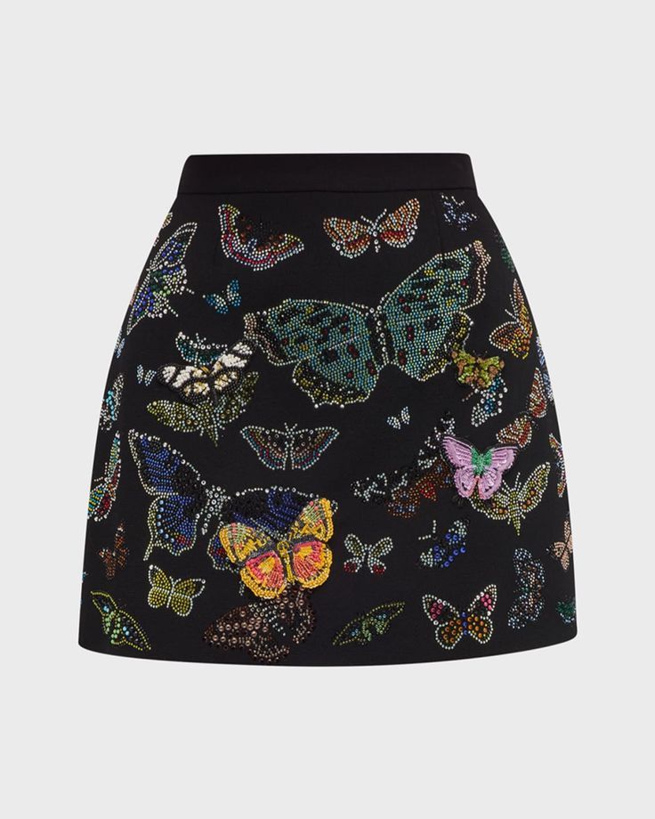 the image shows a black aline mini skirt. the skirt is embellished with beaded and embroidered butterflies of various sizes and colors. the skirt has a highwaisted design. the butterflies add a colorful and decorative element to the black fabric.