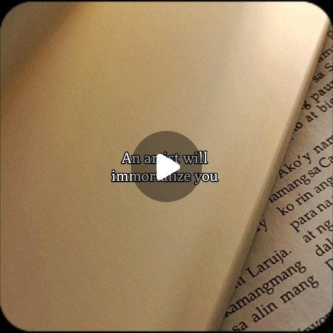 the image shows a closeup of a book's pages, which are a light beige color.  a video play button is superimposed over the image, with the text "an artist will immortalize you" displayed above the play button.  parts of text in what appears to be filipino are visible on the book's pages. the overall aesthetic is simple and minimalist.
