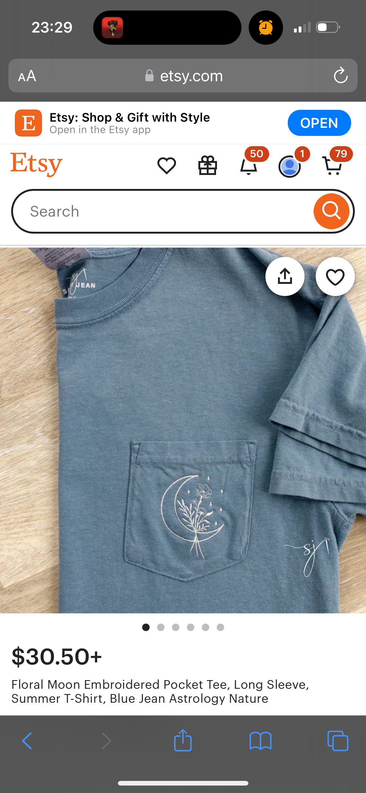 an image of a blue jean fabric tshirt with a pocket on the left chest with an embroidered floral moon design. the image is from the etsy shop and is displayed on the etsy app. the title of the listing says "floral moon embroidered pocket tee, long sleeve, summer tshirt, blue jean astrology nature". the price is listed as $30.50.  the image has a white background and a row of dots at the bottom. there are navigation icons at the bottom of the image that include a back arrow, a forward arrow, a share icon, a bookmark icon, and a shopping cart icon.