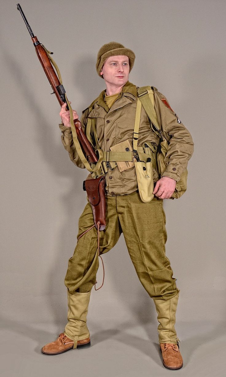 a man dressed in a us army uniform from world war ii, complete with a helmet, rifle, bandolier, and combat boots. he stands with a confident posture, ready for action.