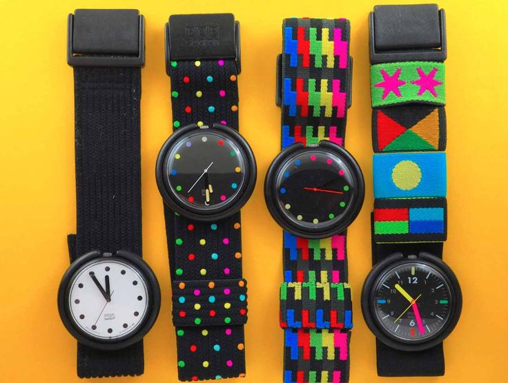 the image shows a collection of four vintage swatch wristwatches with colorful textile straps displayed on a yellow background. each watch has a different strap design, ranging from polka dots to abstract geometric patterns. the watch faces vary as well, including a white face with black markers and black faces with colorful hands. the watches are arranged in a row, showcasing the variety of designs from this retro brand.