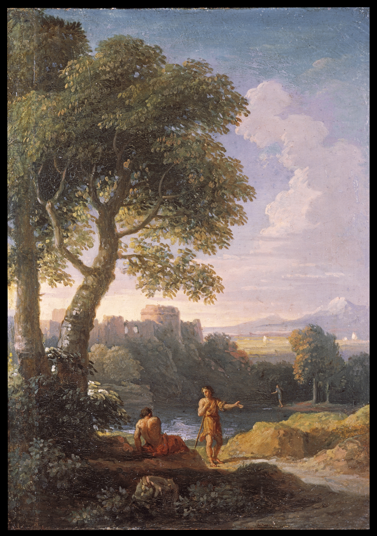 this is a landscape painting depicting a natural scene with several figures. in the foreground, a man is sitting on the ground near the riverbank while another man is standing next to him, holding a stick. there's a large tree on the left side, partially obscuring a ruined building on a hill in the background. the scene includes a river winding through the landscape. a third figure appears to be in the water, further in the background. mountains and a partly cloudy sky can be seen in the distance.