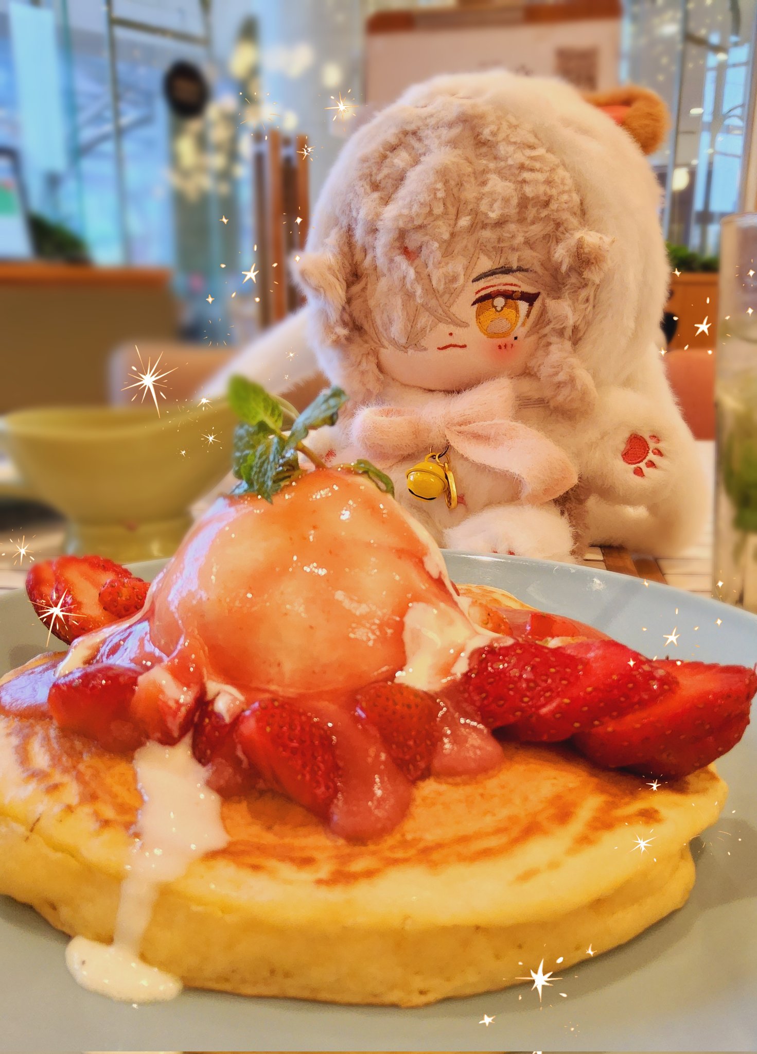 a closeup shot of a pancake with strawberries, whipped cream, and a scoop of ice cream on top. it's a sweet dessert that looks delicious. a cute plush toy is sitting on the table. the plush toy is in a white coat with a pink bow. it appears to be a plush version of a popular anime character.