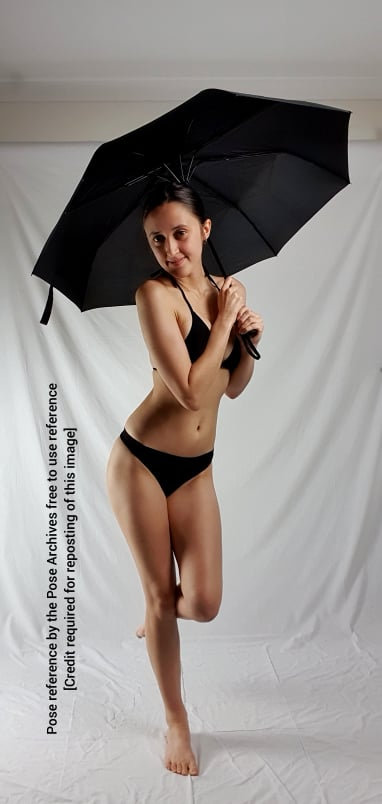 a woman in a black bikini is posing for a reference photo. she is holding a black umbrella and smiling. the background is a white sheet and the lighting is soft.