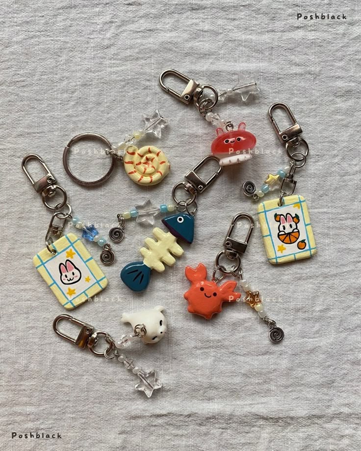 the image shows a collection of handmade keychains with cute cartoonthemed charms, including fish, crabs, seashells, and a rabbit. the keychains are arranged on a textured white surface. each keychain features a different charm and is adorned with beads and various decorative elements.