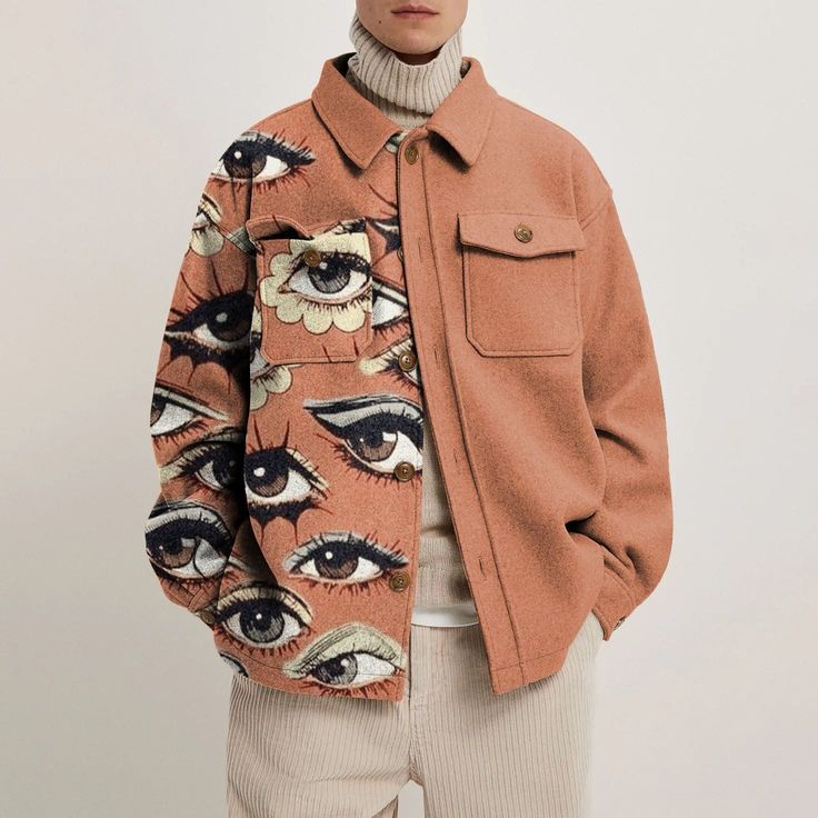 a young man wearing a longsleeved brown jacket featuring a white turtleneck sweater underneath.  the jacket is eyecatching with  a bright print of several eyes with different eye shadow colors.  the model stands with a relaxed and casual pose while looking straight at the camera.