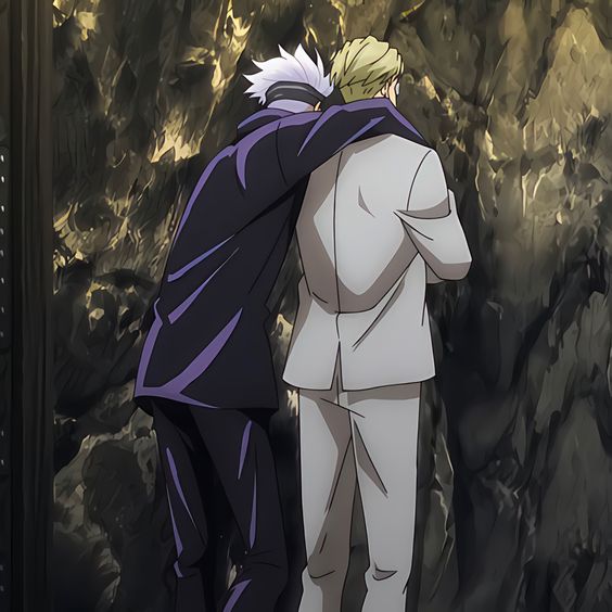 two men stand facing a dark wall with gold accents. they are embracing with the man on the left's arm draped over the shoulders of the man in white.  both men are seen from the back.  the scene is dark with dramatic lighting highlighting the figures.