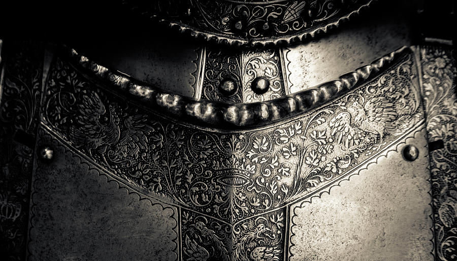 the image showcases a closeup view of an intricately engraved breastplate, a central component of a medieval suit of armor. crafted from metal, the armor features elaborate floral patterns, highlighting the craftsmanship prevalent in that era. the interplay of light and shadow accentuates the armor's metallic texture, lending a sense of depth and history to the image.