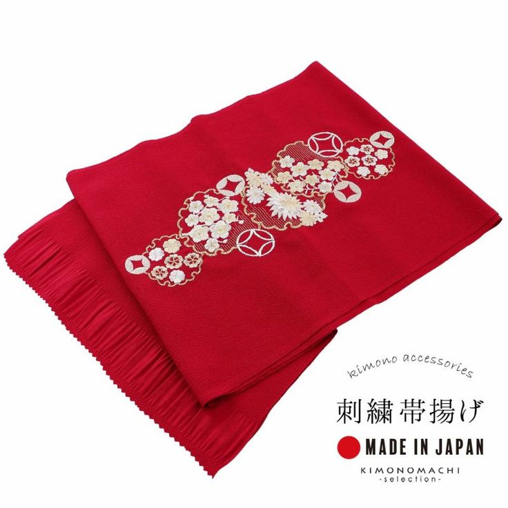 a red kimono accessory with white and gold floral embroidery is displayed on a white background. the fabric is partially pleated, and text in japanese and english with the phrase "made in japan" is visible below the fabric.
