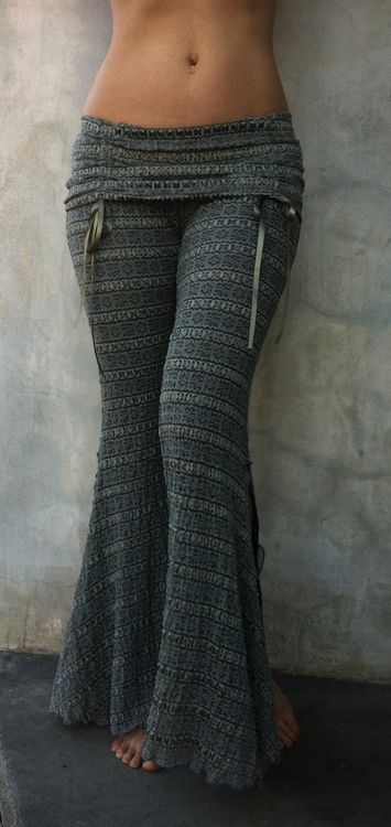 a woman is standing on a white background wearing a pair of grey flared pants with a thin grey belt at the waist. she is looking straight at the camera and her face is not visible.