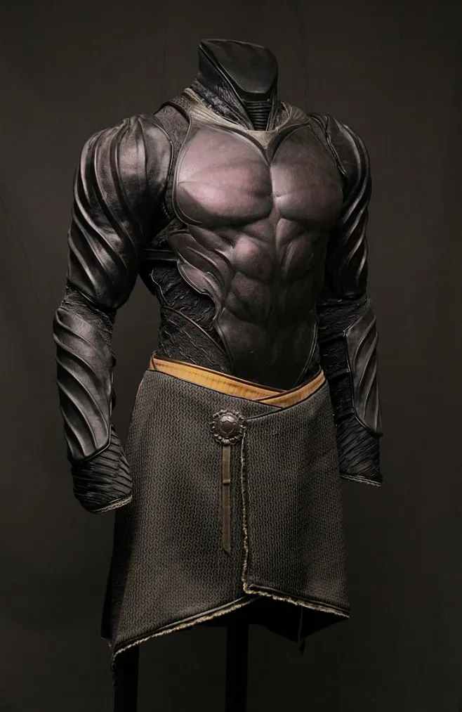 the image showcases a sculpted torso of a male figure clad in intricately detailed, dark fantasy armor. the armor boasts a muscular aesthetic with flowing lines and a combination of smooth and textured surfaces. it features a chest plate, shoulder guards that extend down the arms, and a kiltlike garment around the waist. a simple goldcolored belt with a circular buckle cinches the kilt. the lighting is soft and diffused, highlighting the details and textures of the sculpture while maintaining a dramatic mood. the background is a dark, neutral gray, further emphasizing the figure.