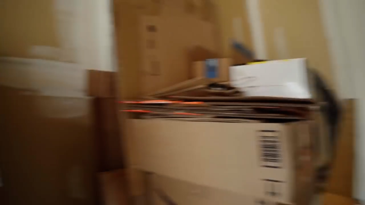a stack of cardboard boxes sits in a room.  some of the boxes are open. the wall appears to be yellow.