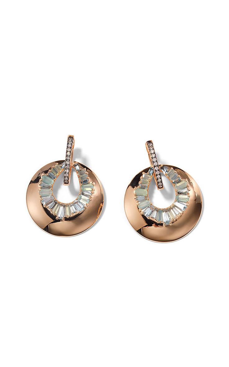 two gold earrings with a circular design and set with baguette diamonds. the earrings are on a white background.