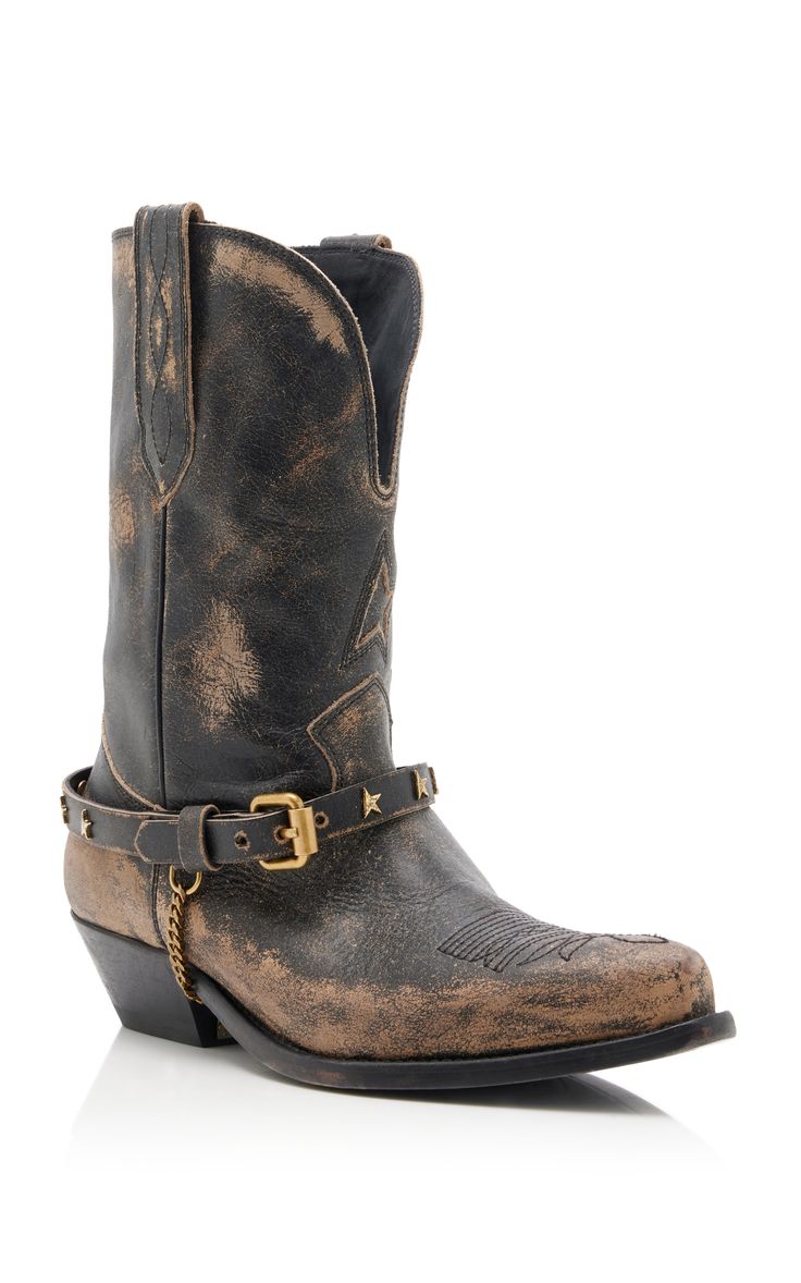 a pair of women's black distressed leather cowboy boots with a studded strap around the ankle are displayed against a white background. the boots are shown from a slightly angled view.  the leather appears worn and has a faded, vintage look.  the studs on the strap are goldtoned. the boots have a slightly pointed toe.