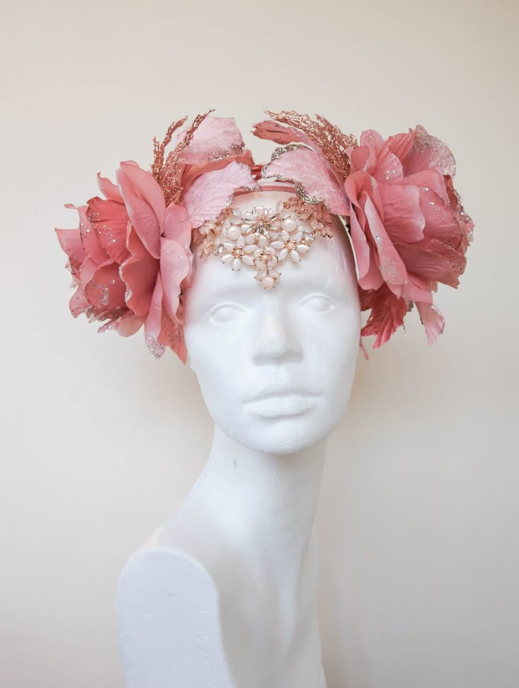 a headwear consisting of a floral crown with pink flowers and beads, displayed on a mannequin head. the headwear is the main subject of the image.