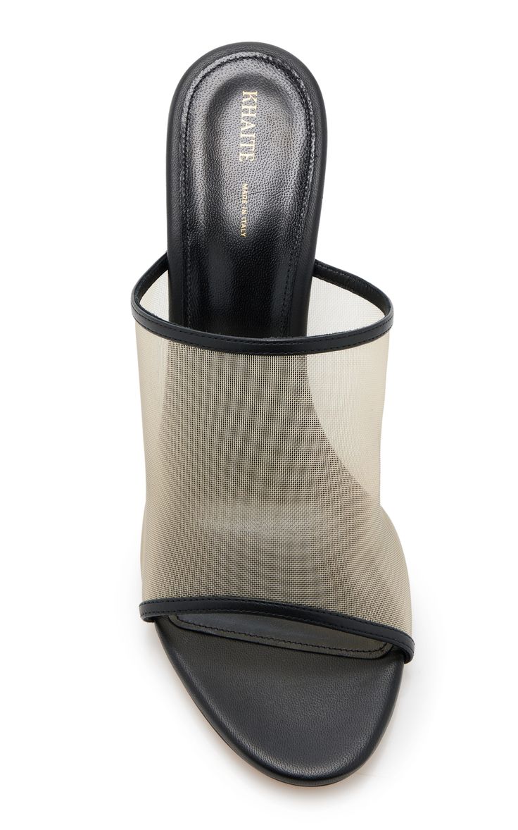 the image showcases a pair of khaite black mesh mules.  the shoes feature a black leather insole and heel, with a beige mesh upper that's opentoed. the "khaite" brand name is subtly visible on the insole. the shoes are presented against a white background, highlighting their design details.
