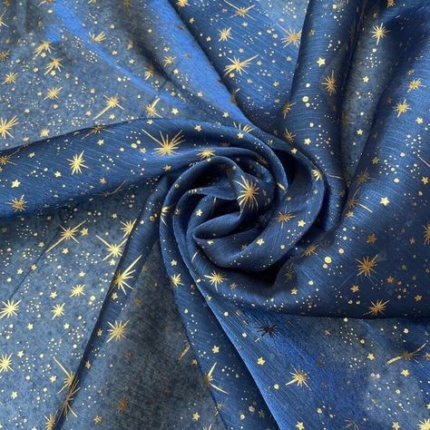 the image is of a blue piece of fabric with a gold star and shooting star pattern. the fabric appears to be silk or some other thin material.