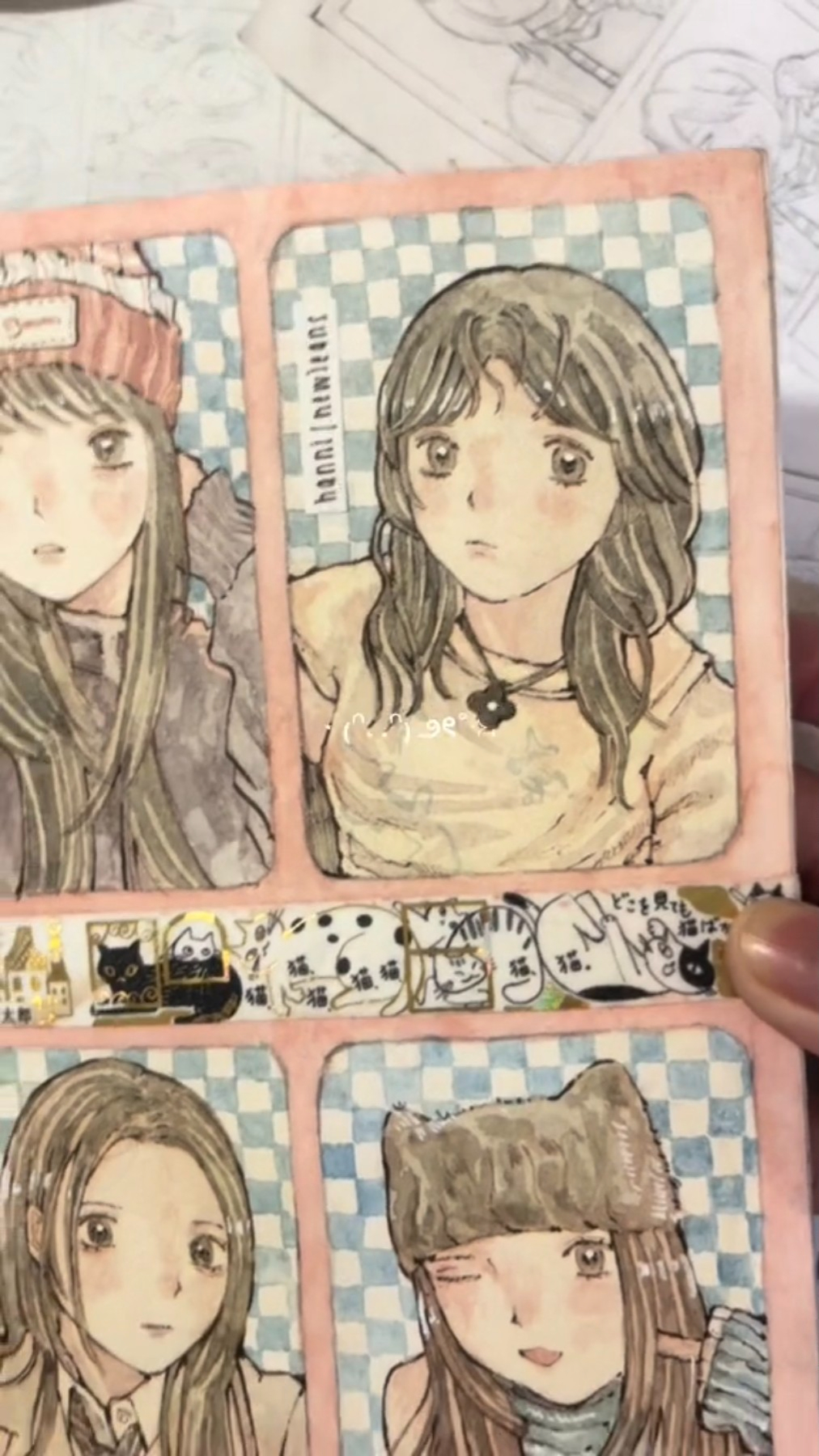 a drawing of three anime girls. each girl is in a separate box. all three have long brown hair and are wearing different outfits. the boxes have a checkered background and are bordered by pink. there is a stripe of stickers at the bottom of the boxes featuring cats and houses.