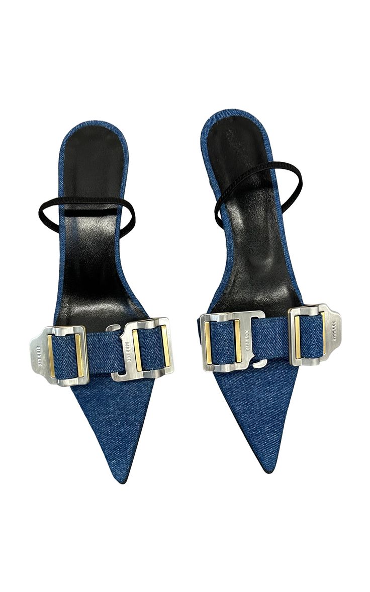 a pair of women's denim high heel sandals are shown against a white background. the sandals are made of denim material and have silver buckles on the straps. the heels are pointy and the straps wrap around the ankles.