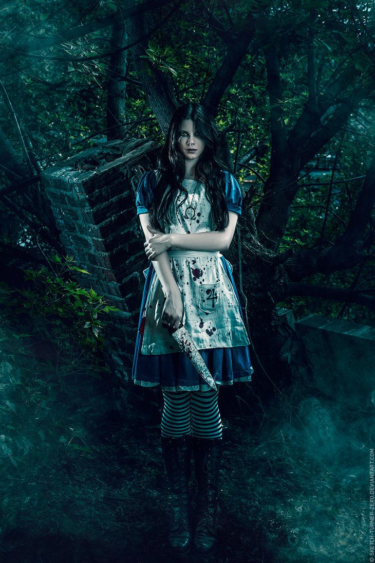 a captivating cosplay photograph depicts a young woman dressed as alice from american mcgee's alice. she's standing in a dark, atmospheric forest setting, holding a bloody knife. her dress is stained with blood, mirroring the game's dark and twisted atmosphere.  the overall mood is gothic, mysterious, and slightly unsettling. the image's lighting and composition enhance the overall dark and macabre tone.  the model's expression is serious and intense.