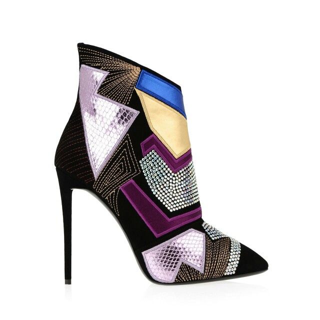 a closeup shot of a black women's ankle boot with a pointed toe. the boot is adorned with rhinestones and other colorful embellishments in a geometric pattern. the heel is very high and slender. the boot is photographed on a white background.