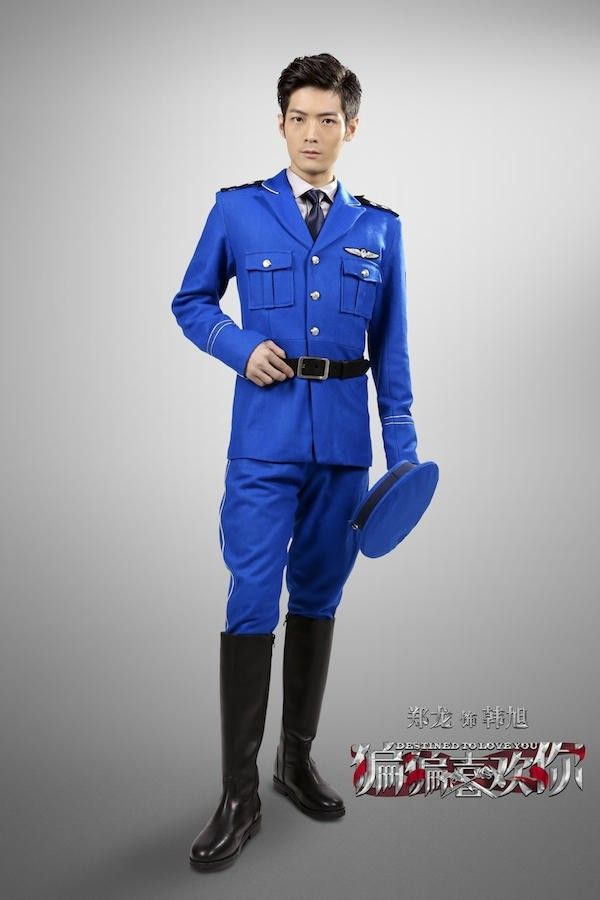 a full shot of a man wearing a blue pilot uniform, black belt and boots, and holding a hat, with the words "zheng long han zhe" and a logo at the bottom right corner.