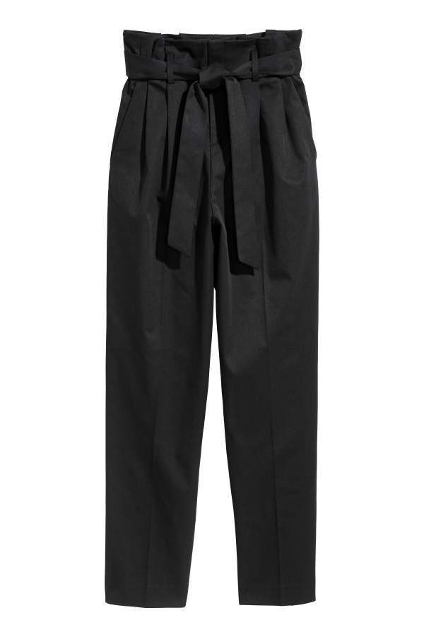 a studio shot of a pair of black, highwaisted pants with a paper bag waist and tie belt. the pants are cropped with a straight leg and feature pleats at the waist.