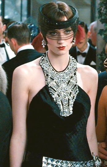 a woman wearing a black velvet dress with a sparkling diamond necklace and headband. she is at a party and looks elegant and glamorous. she is wearing makeup and has her hair styled in a bob. the image is taken close up and focuses on her face and head. she is looking directly at the camera.
