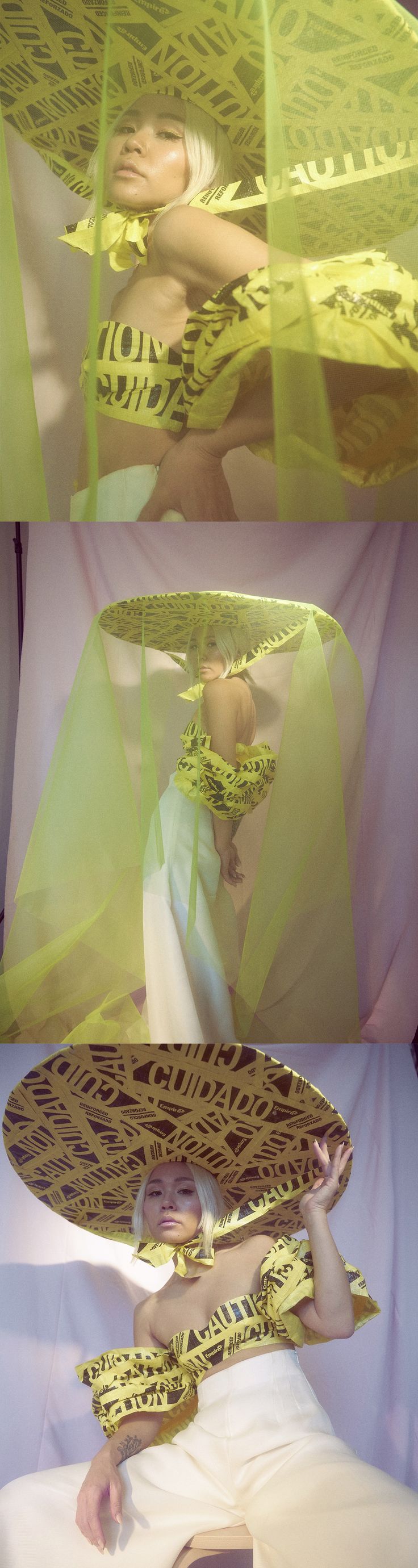 the image is a triptych of fashion photography showcasing a model wearing three variations of a striking outfit.  the core element is a large, widebrimmed hat and coordinating clothing made from or incorporating bright yellow caution tape. the model wears an offtheshoulder top and loose, widelegged pants in each image, maintaining a similar pose throughout. the background is a muted pastel color, providing contrast with the bright yellow of the attire. the style leans toward avantgarde, conceptual high fashion, showcasing a creative and unusual approach to clothing design and presentation. the fabric is draped and layered artfully, emphasizing the ethereal and dramatic nature of the photoshoot.