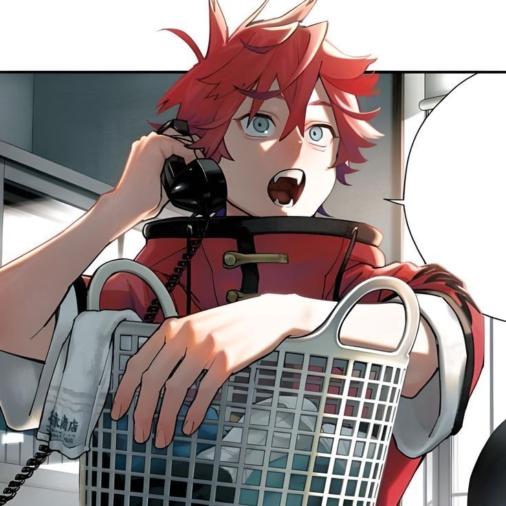 an anime boy with bright red hair wearing a red shirt is on the phone while holding a laundry basket. he is looking into the distance and talking. the room has white walls and a gray floor.  there are also black and white items in the background.