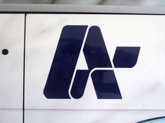 a closeup photograph of a blue logo on a white background. the logo appears to be a stylized letter "a" with a winglike element extending from the right side. the background suggests it might be affixed to a vehicle or a structure.