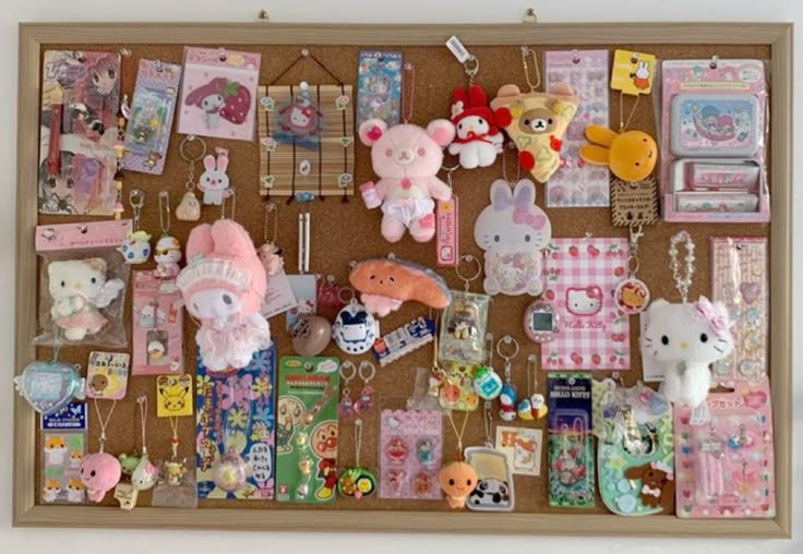 a framed corkboard covered in a collection of sanrio and other kawaii character items. there are various plush toys, keychains, pins, charms, and packaged accessories featuring characters like hello kitty, my melody, rilakkuma, little twin stars, anpanman, tamagotchi, and pikachu. the color scheme is dominated by pinks, pastels, and other cute, japaneseinspired designs. the items are pinned to the board with pushpins.